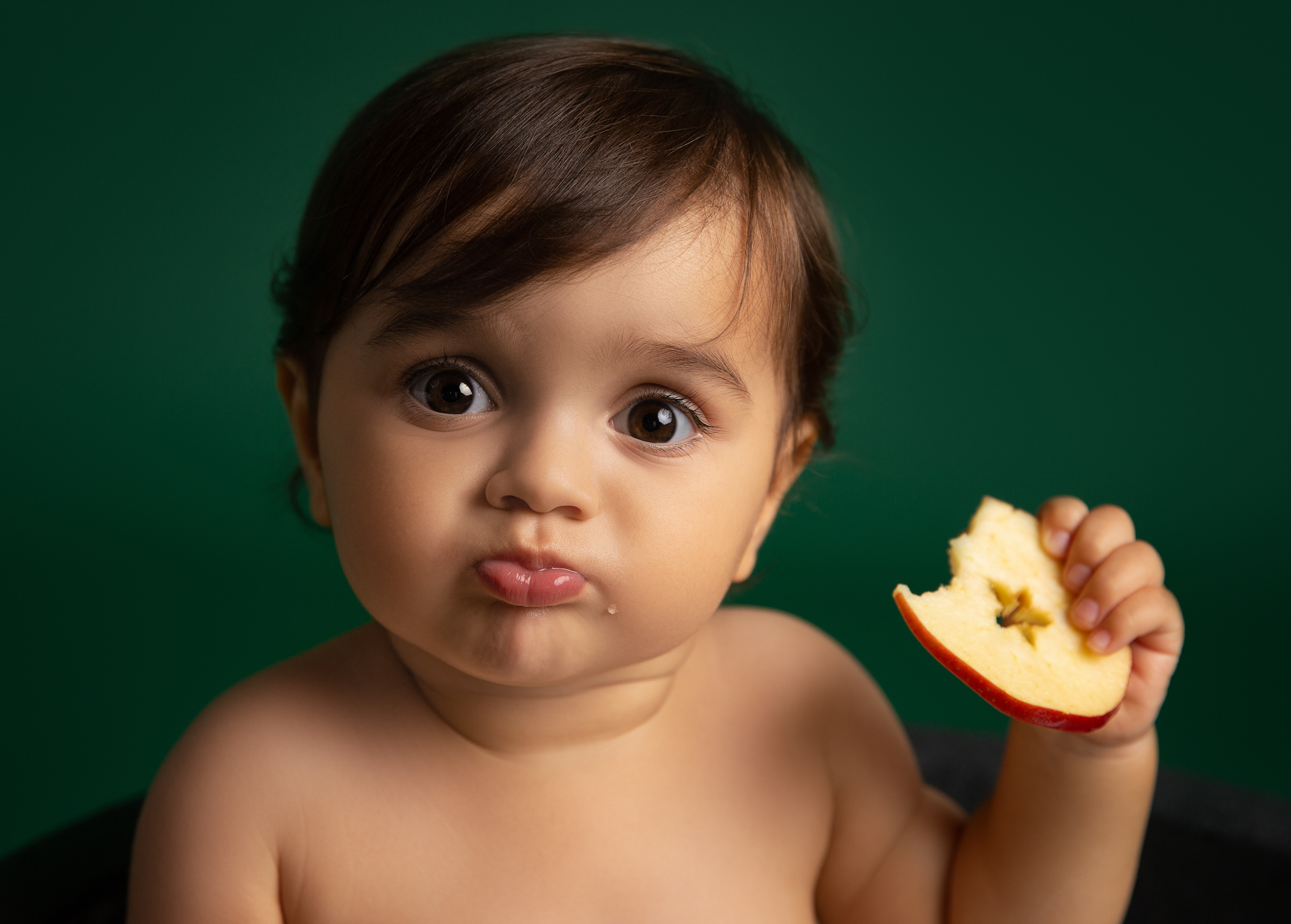 Close up shot of a 1 year old eating a slice of apple in Sandbach, Cheshire