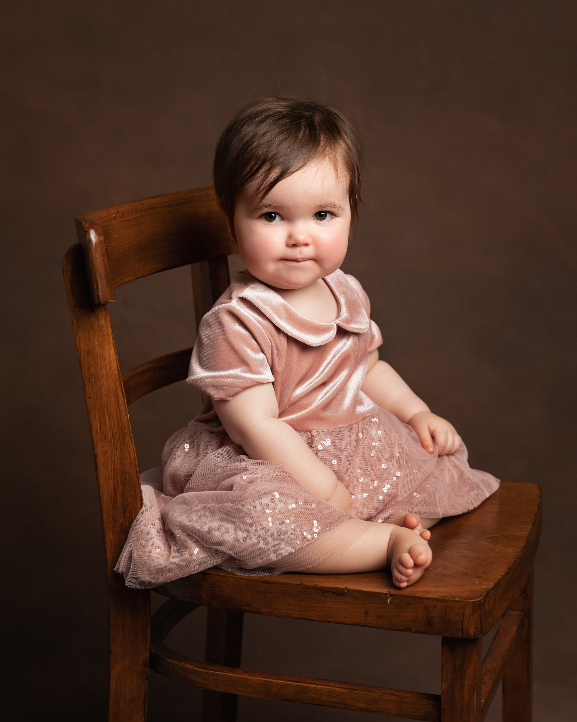 1 year old girl sitting on a chair during her birthday shoot in Sandbach, Cheshire