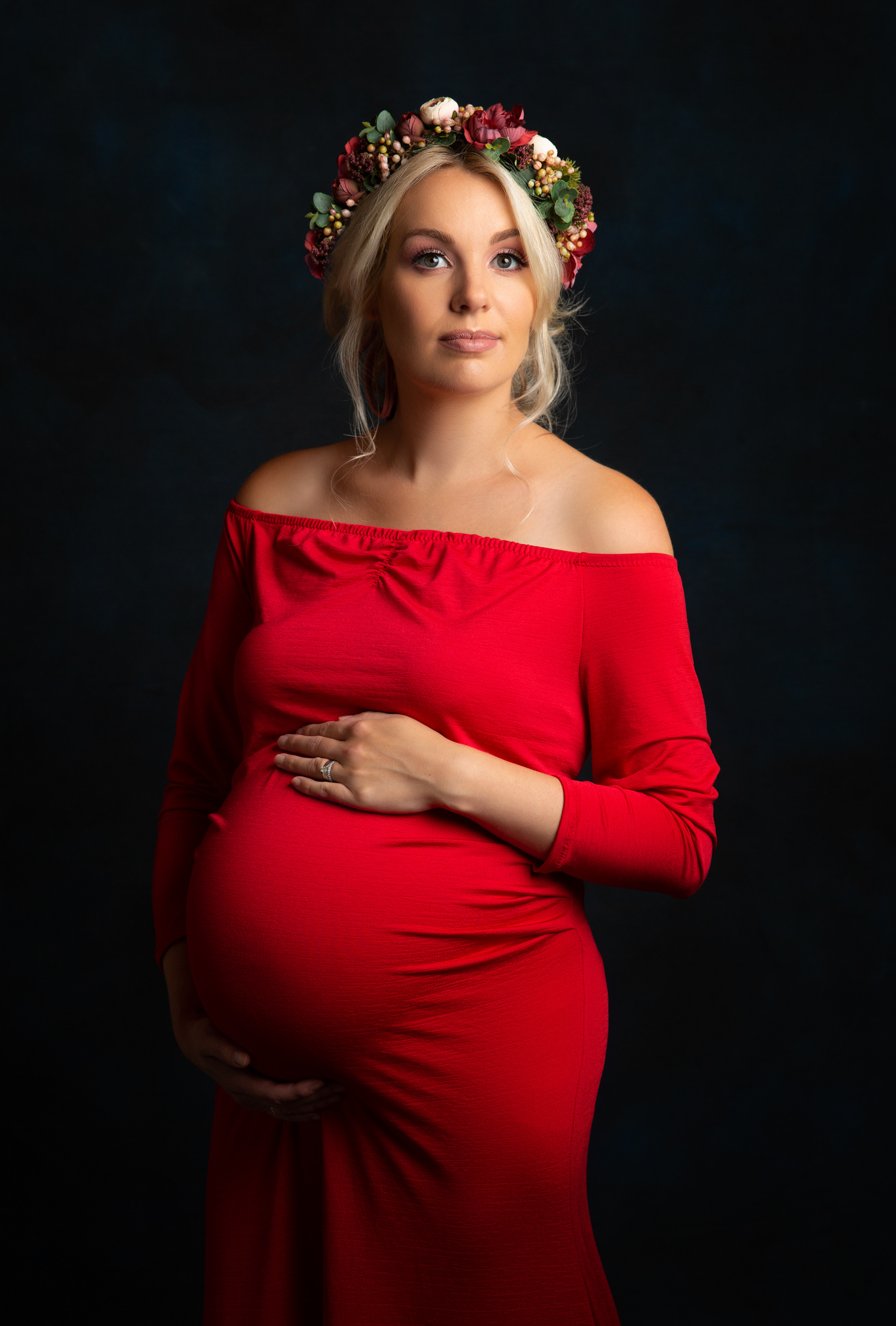 Beautiful pregnant lady in a bright red dress with floral headband at her maternity photo shoot in Sandbach, Cheshire