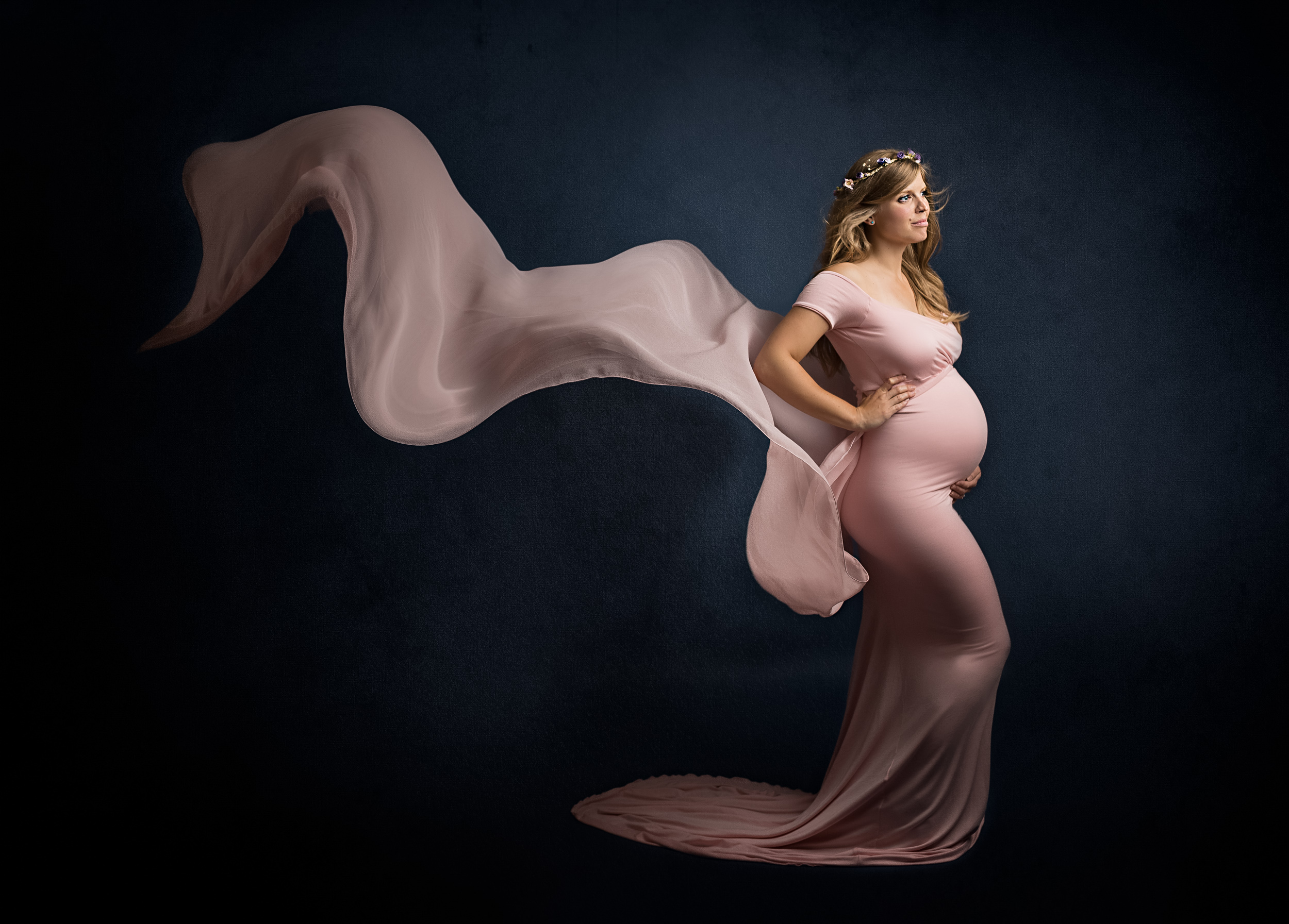 Side pose of a pregnant lady in a floating pink dress at her maternity photo shoot in Sandbach, Cheshire