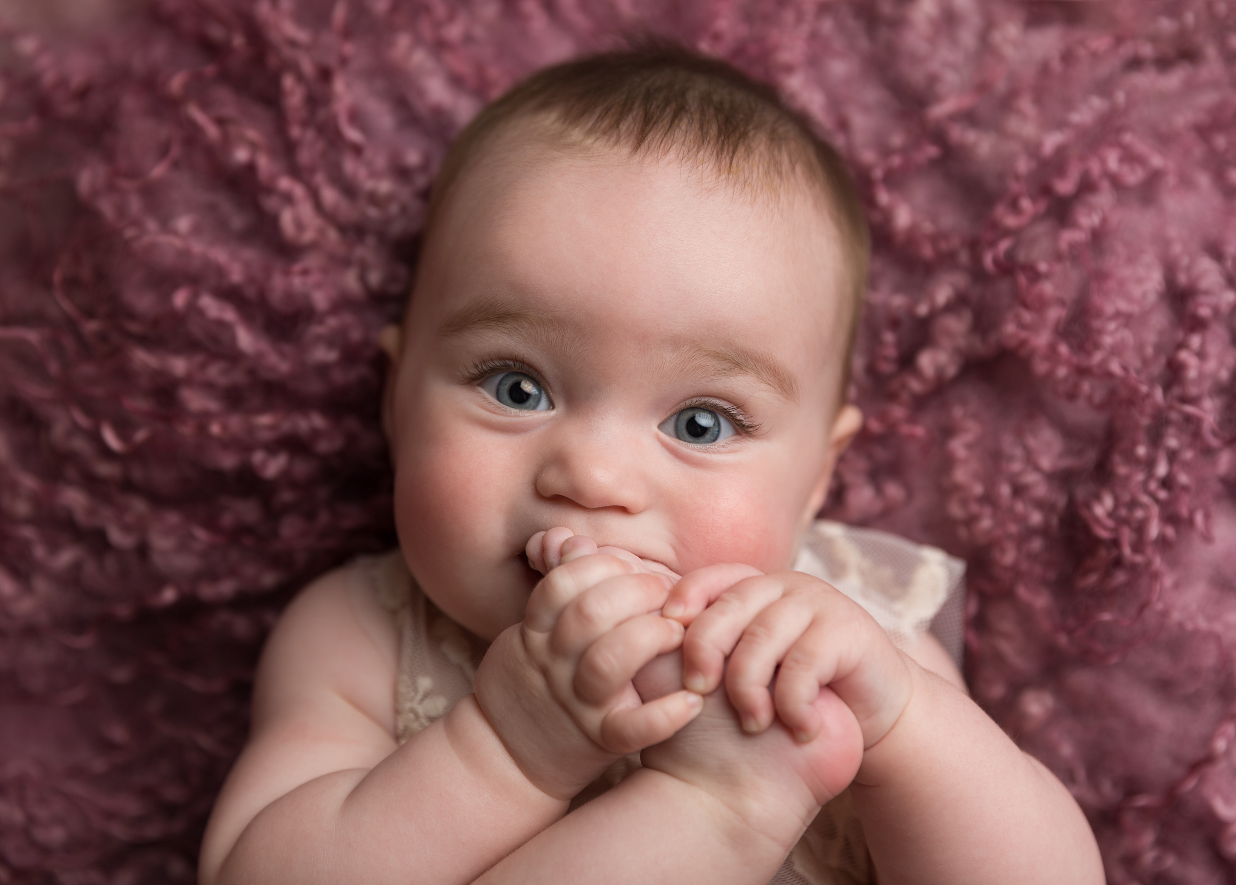 Little baby girl chewing her foot taken during a milestone portrait session in Sandbach, Cheshire