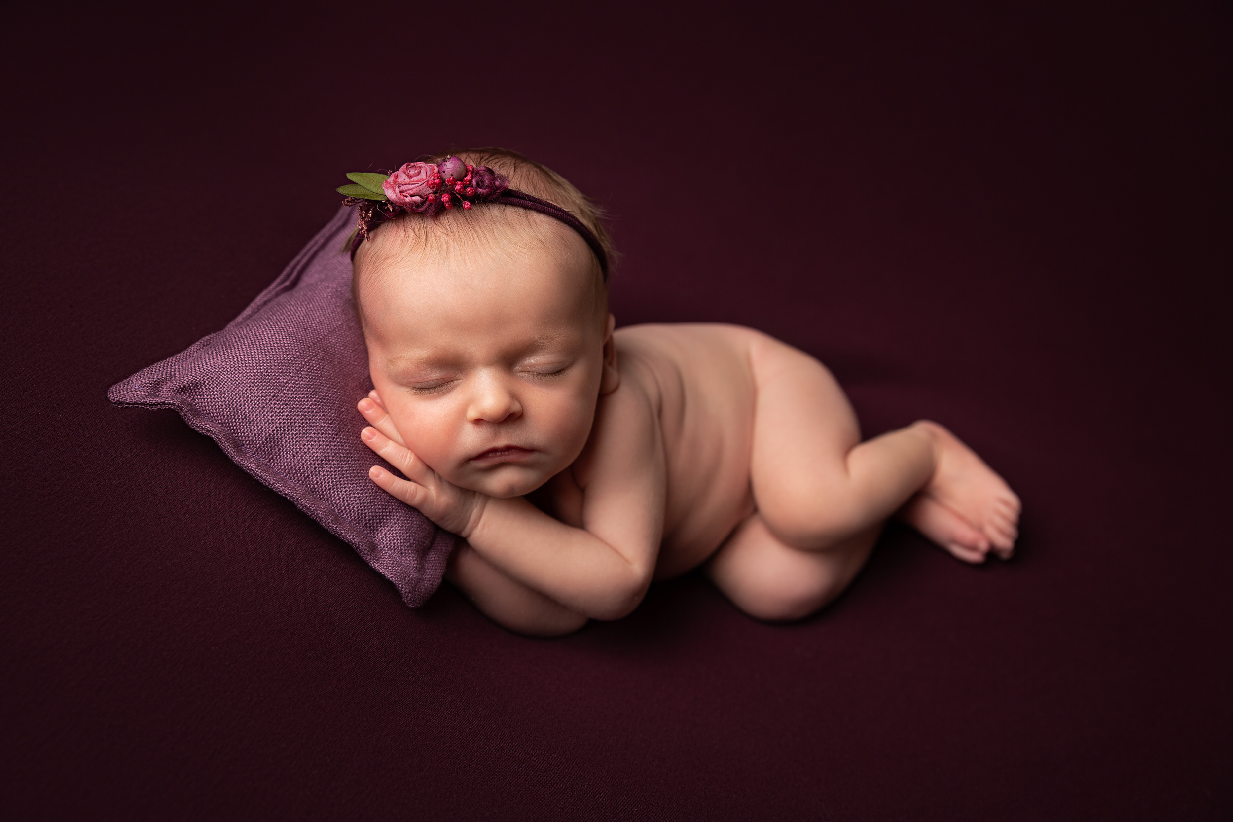 Posed newborn baby with purple colour schemeby Cheshire newborn photographer in Sandbach
