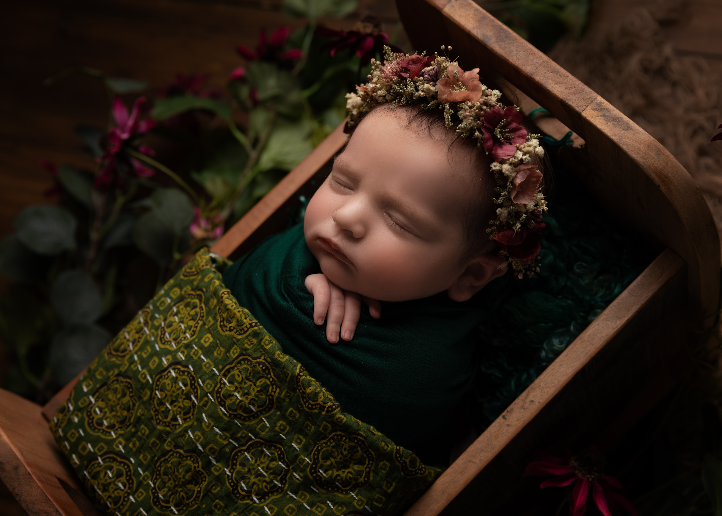 Baby girl in newborn bed with green and purple colour scheme by Cheshire newborn photographer in Sandbach