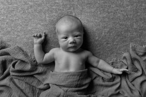 Newborn baby lying awake with a wrap on in black and white by Cheshire newborn photographer in Sandbach