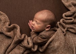 cosy warm newborn baby posed with wrap draped over by Cheshire newborn photographer in Sandbach