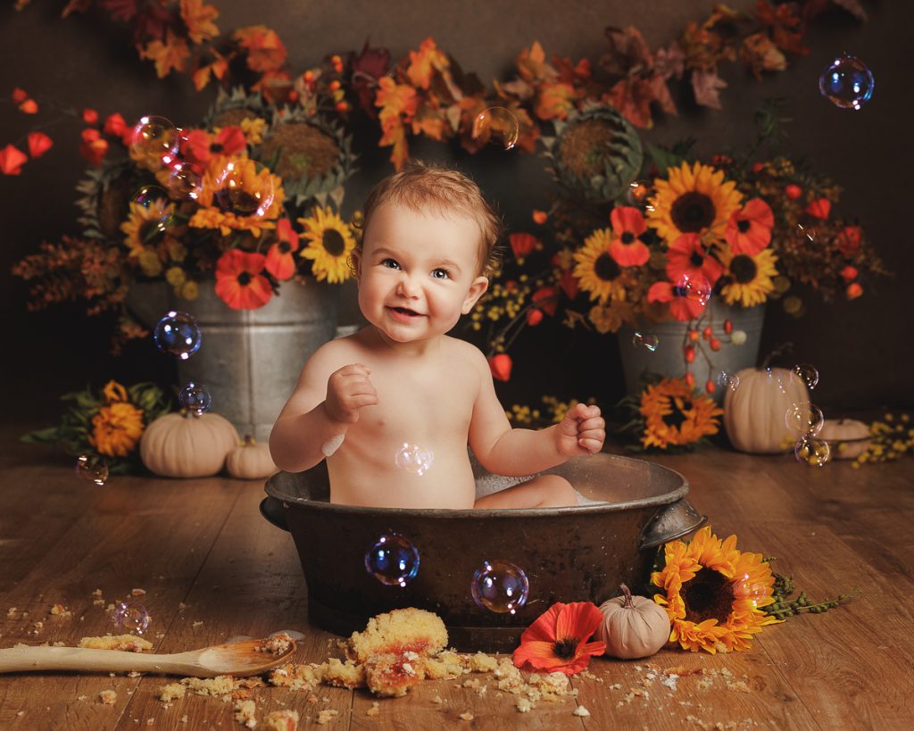 Little girl enjoying a splash after her first birthday cake smash photoshoot in my Sandbach studio.